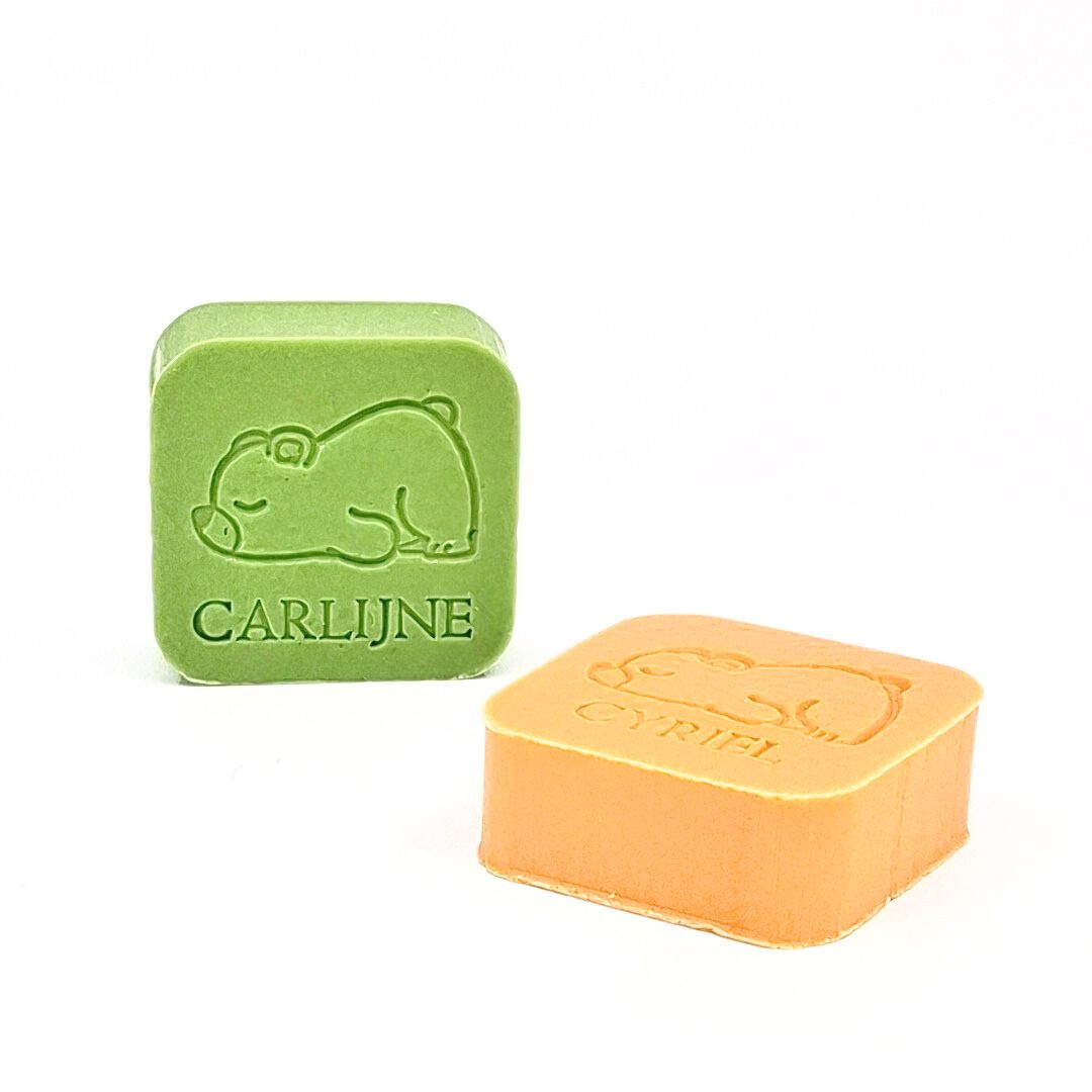 een rechtopstaand zeepje met opdruk beertje en naam in kleur appel en een liggend zeepje in kleur kamperfoelie