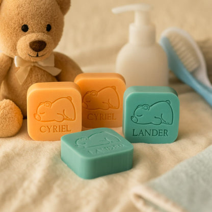 een sfeerfoto van vierkante zeepjes in de kleuren kamperfoelie en zeealgen met een opdruk van een beertje en naam 