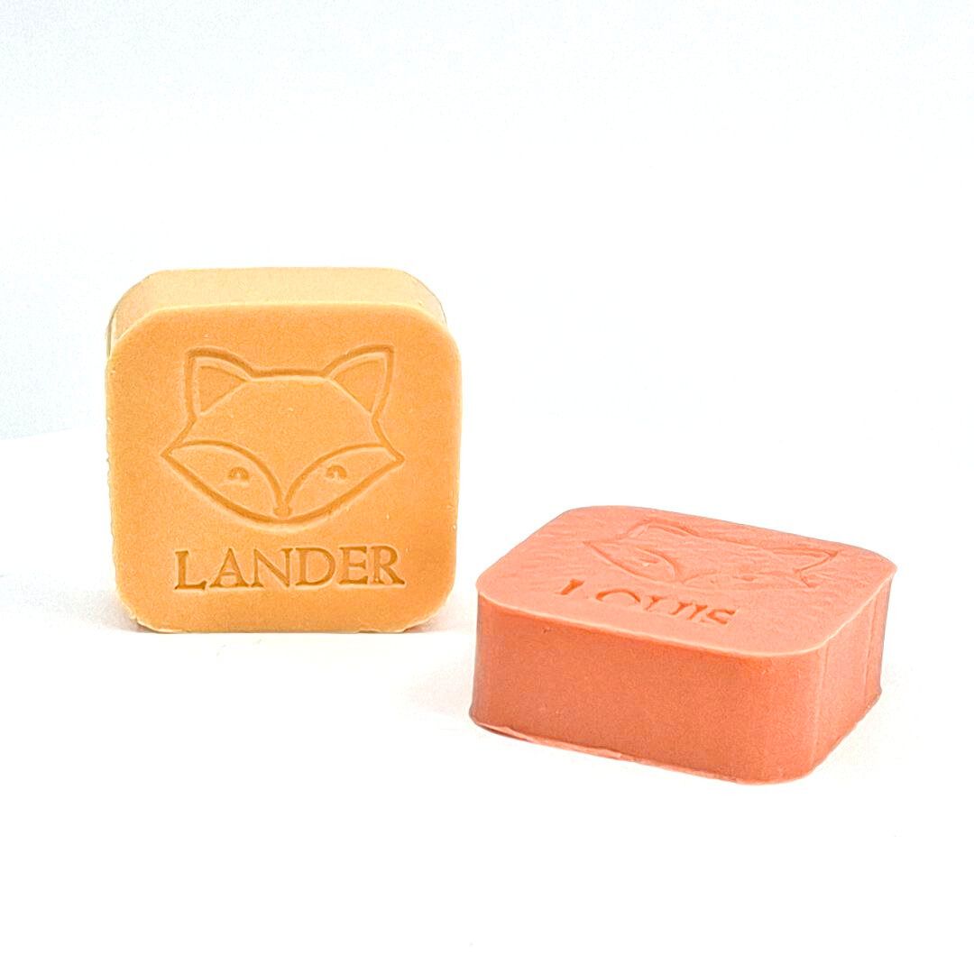 Twee zeepjes met opdruk vos en naam in de kleuren bruce en kamperfoelie