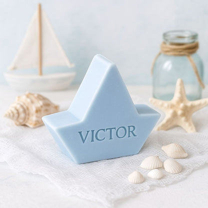 Lichtblauw zeepje in de vorm van een bootje bedrukt met de naam VICTOR. Op de achtergrond een zee thema.