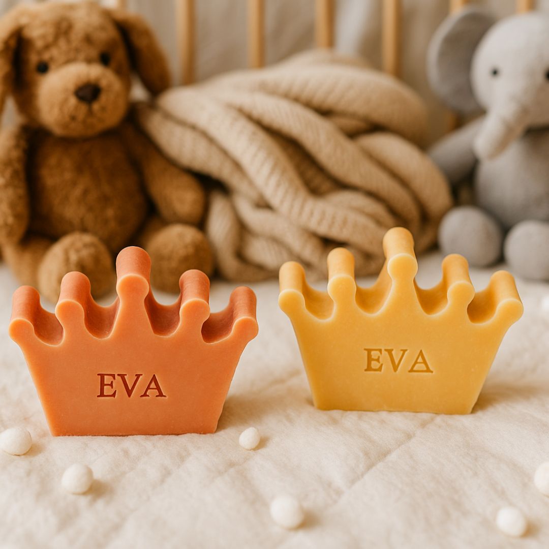 Twee oranjekleurige zeepjes on kroonvorm met op de achtergrond een knuffelbeer en olifant.