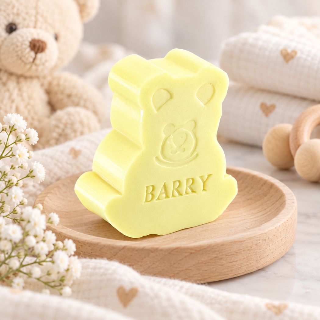 Gepersonaliseerd beerzeepje met de naam Barry in de kleur mimosa, sfeervol gepresenteerd op een houten schaaltje met zachte babytextielen, teddybeer en houten accessoires.