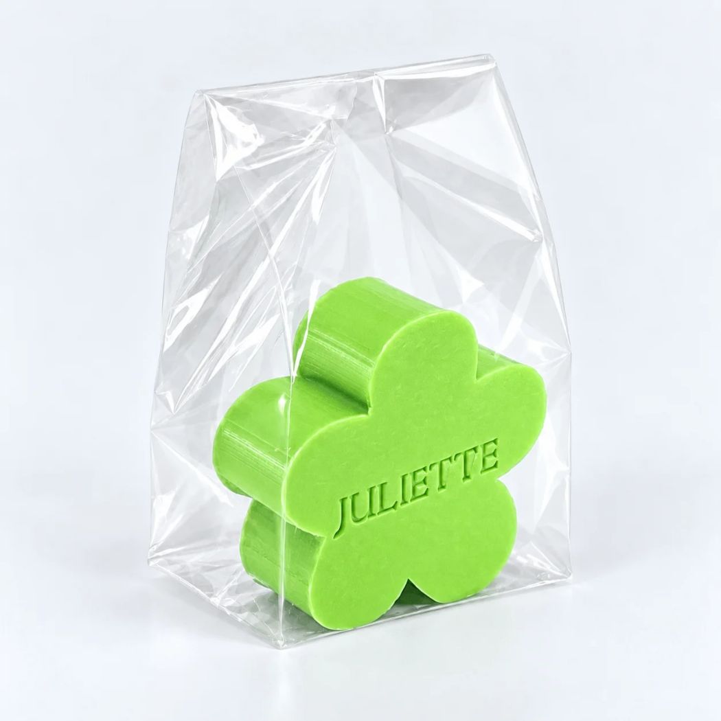 Gepersonaliseerd bloemvormig zeepje met de naam Juliette, in de kleur appel, verpakt in een transparant zakje op een lichte achtergrond.
