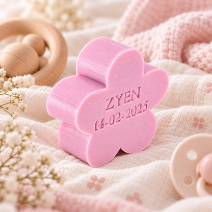 Gepersonaliseerd bloemvormig zeepje met de naam Zyen en datum 14-02-2025, in de kleur violet, sfeervol gepresenteerd met zacht babytextiel, houten speelgoed en subtiele bloemen.