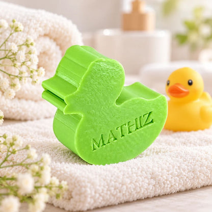 Gepersonaliseerd eendvormig zeepje met de naam Mateiz in de kleur appel, sfeervol gepresenteerd met zachte badtextielen, witte bloemen en een geel badeendje.