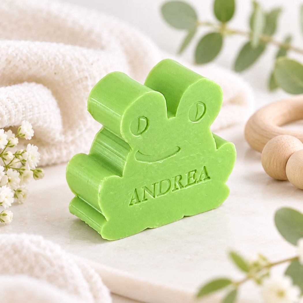 Gepersonaliseerd kikkerzeepje met de naam Andrea in de kleur appel, sfeervol gepresenteerd met zachte lichte textielen, houten accessoires en groene accenten.