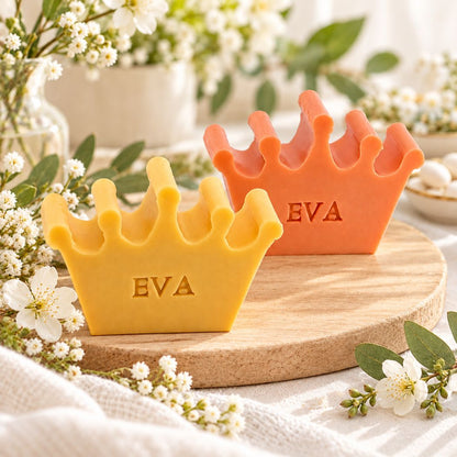 Gepersonaliseerde kroonvormige zeepjes met de naam Eva in de kleuren kamperfoelie en bruce, sfeervol gepresenteerd in een frisse lentefeestsetting met witte bloesems en groene accenten.