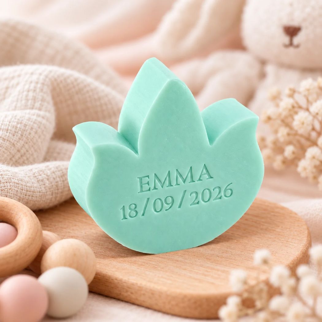 Gepersonaliseerd zeepje in de vorm van een tulp met de naam Emma en datum 18/09/2026, in de kleur muguet, sfeervol gepresenteerd met zachte neutrale tinten en houten babyaccessoires.