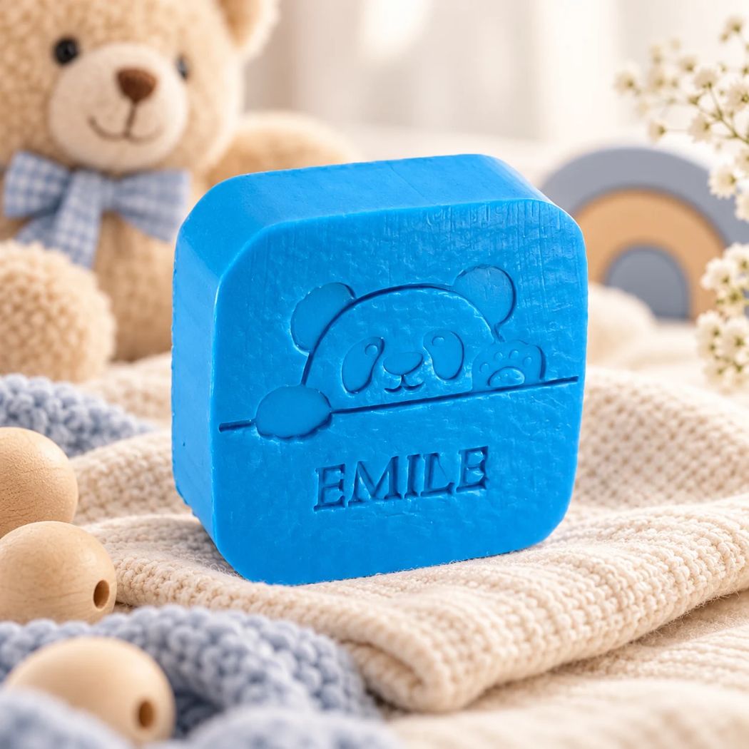 Blauw vierkant zeepje met panda en de naam Emile, in de kleur azuur, sfeervol gepresenteerd met zachte babytextielen, houten accessoires en een teddybeer.