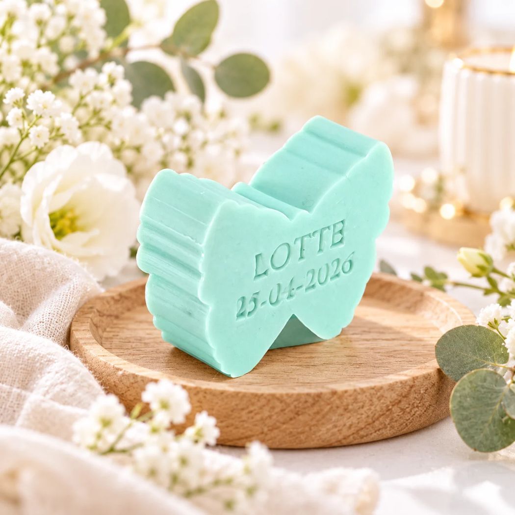 Gepersonaliseerd zeepje in de vorm van een vlinder met de naam Lotte en datum 25-04-2026, in de kleur muguet, sfeervol gepresenteerd voor communie of lentefeest met zachte witte bloemen en natuurlijke accenten.