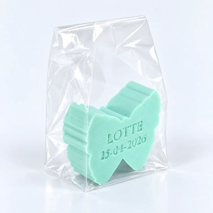 Muntgroen vlinderzeepje met naam Lotte en datum 25-04-2026 in een transparant geschenkzakje op een lichte achtergrond.