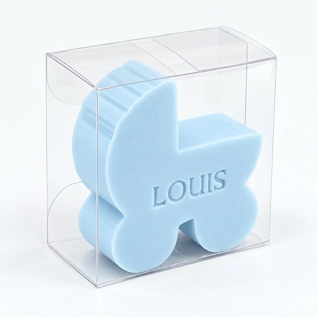 Gepersonaliseerd zeepje in de vorm van een wiegje met de naam Louis, in de kleur pari, verpakt in een transparant doosje op een lichte achtergrond.