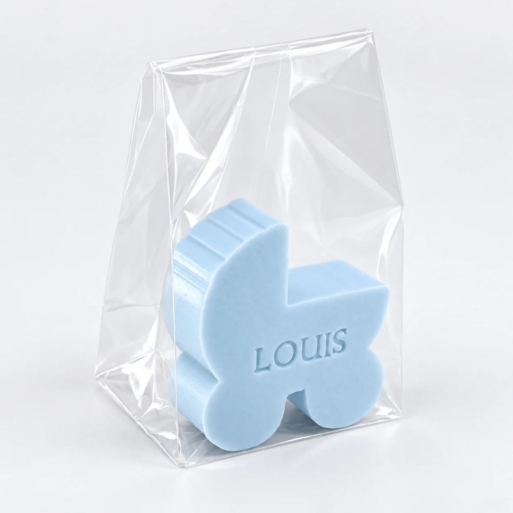 Gepersonaliseerd zeepje in de vorm van een wiegje met de naam Louis, in de kleur pari, verpakt in een transparant zakje op een lichte achtergrond.