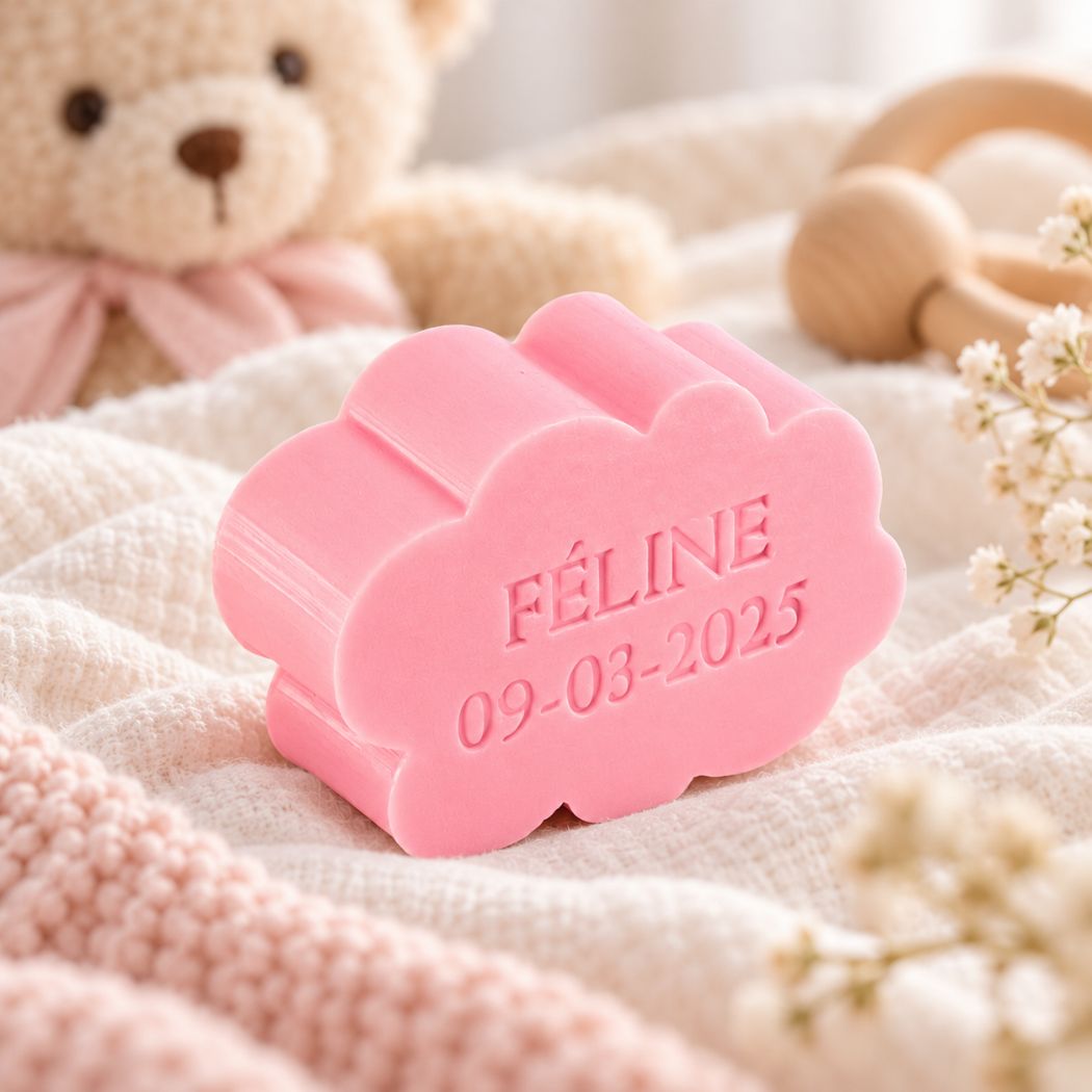 Gepersonaliseerd wolkvormig zeepje met de naam Féline en datum 09-03-2025, in de kleur rozen, sfeervol gepresenteerd in een zachte babysetting met teddybeer, babytextiel en houten speelgoed.