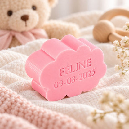 Gepersonaliseerd wolkvormig zeepje met de naam Féline en datum 09-03-2025, in de kleur rozen, sfeervol gepresenteerd in een zachte babysetting met teddybeer, babytextiel en houten speelgoed.