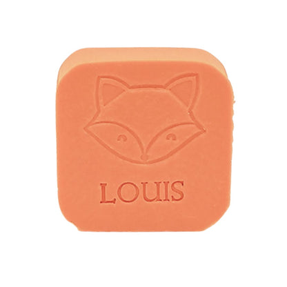 Vierkant oranje zeepje met ingegraveerde vos en naam "LOUIS", recht van voren gefotografeerd tegen witte achtergrond.